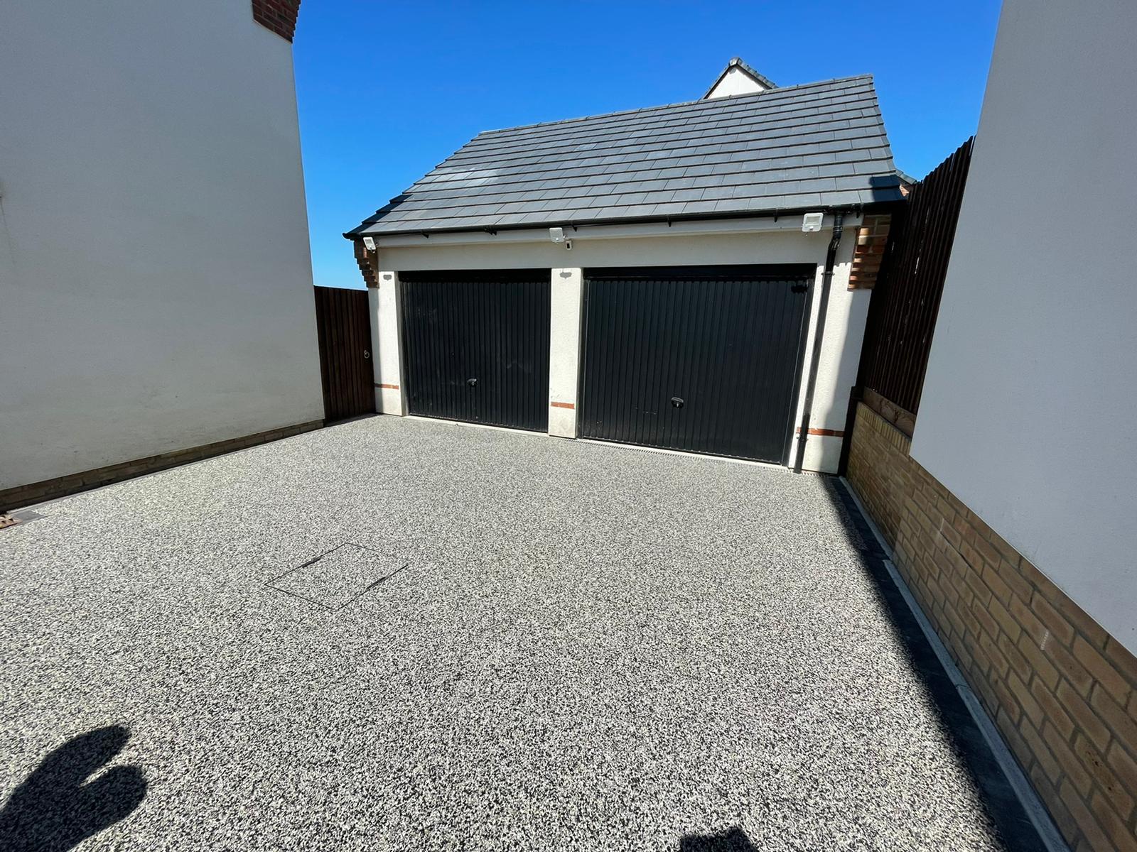 Silver resin driveway leading to a double garage