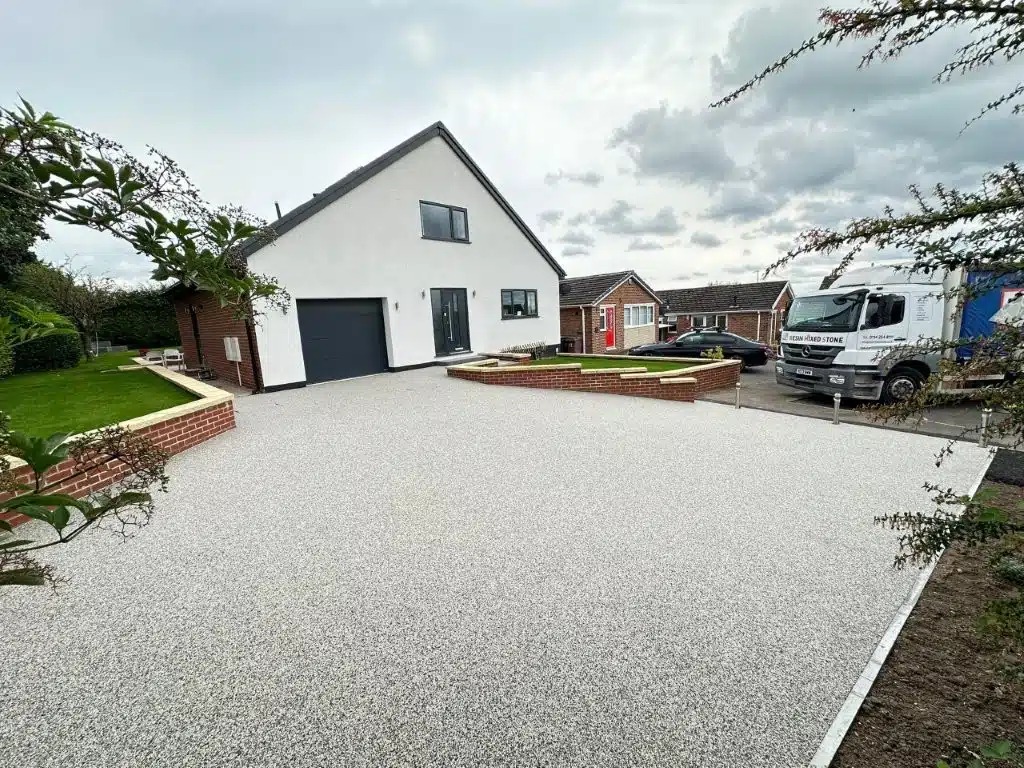 Large light-coloured driveway surface beside a white property