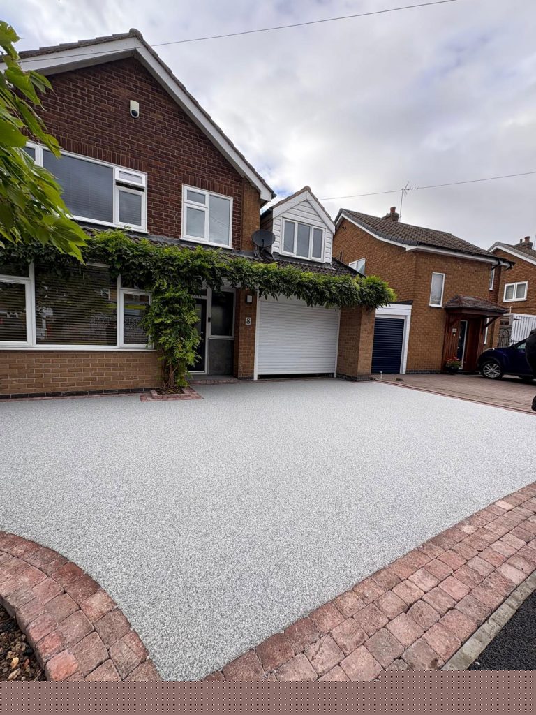 Silver-grey resin driveway with a brick border
