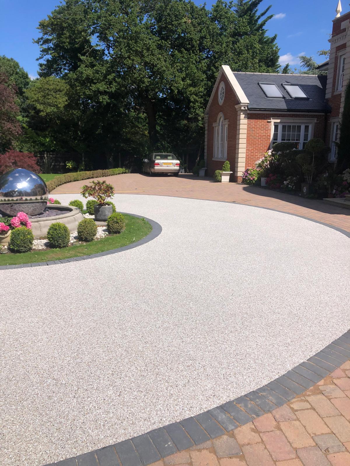 Warm resin driveway shaped around a circular landscaped garden