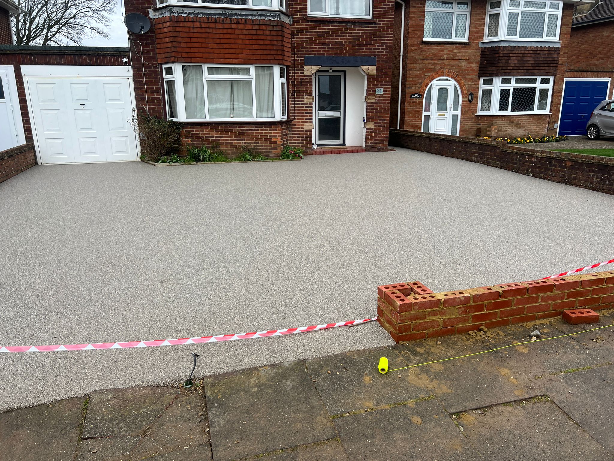 Broad neutral resin driveway across the front of a home