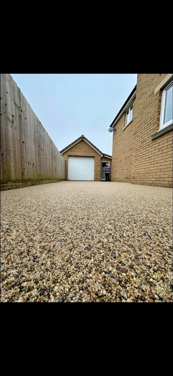 A completed warm-toned resin surface leading to a garage