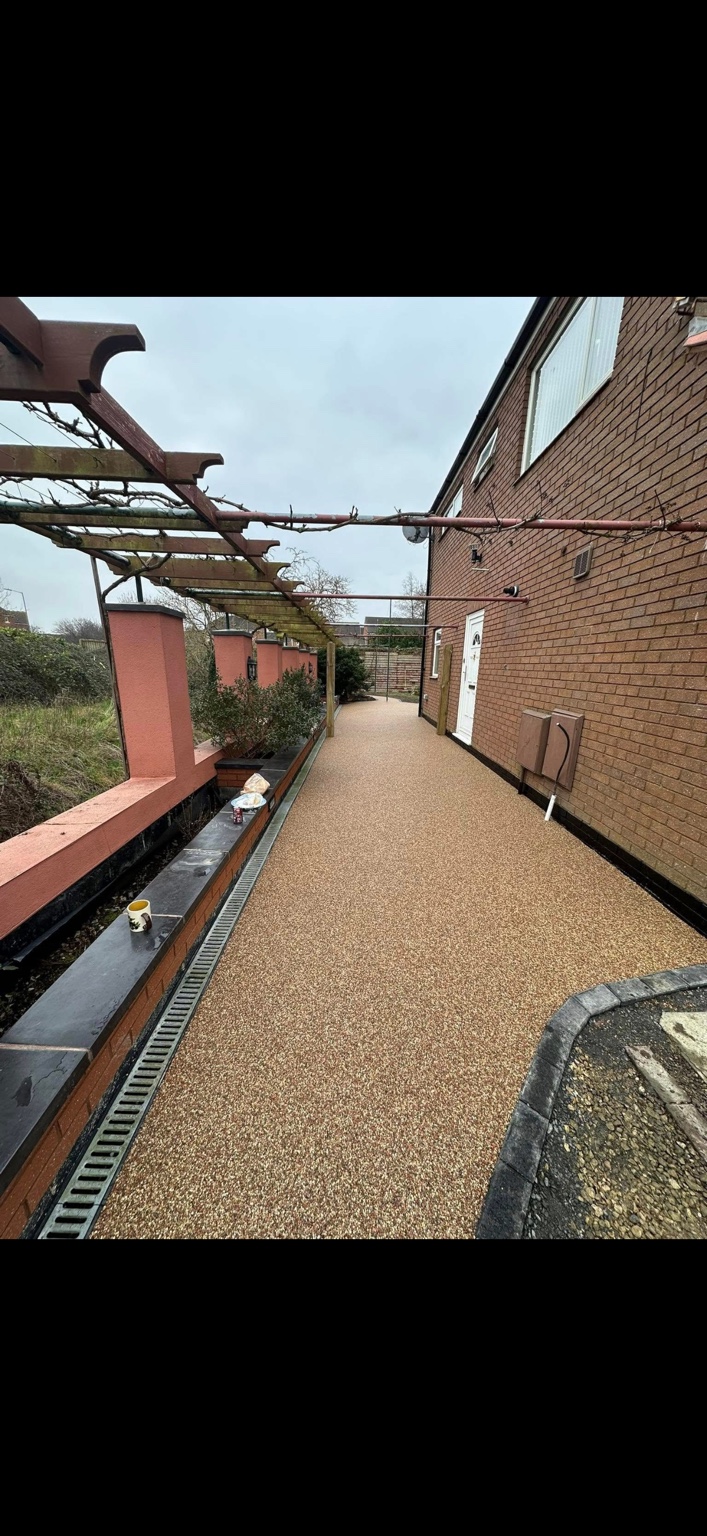 A completed warm-toned resin pathway beside a home
