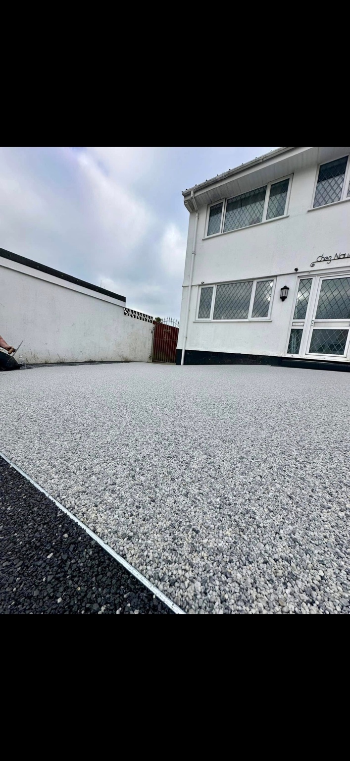 A completed light grey resin driveway viewed from the entrance
